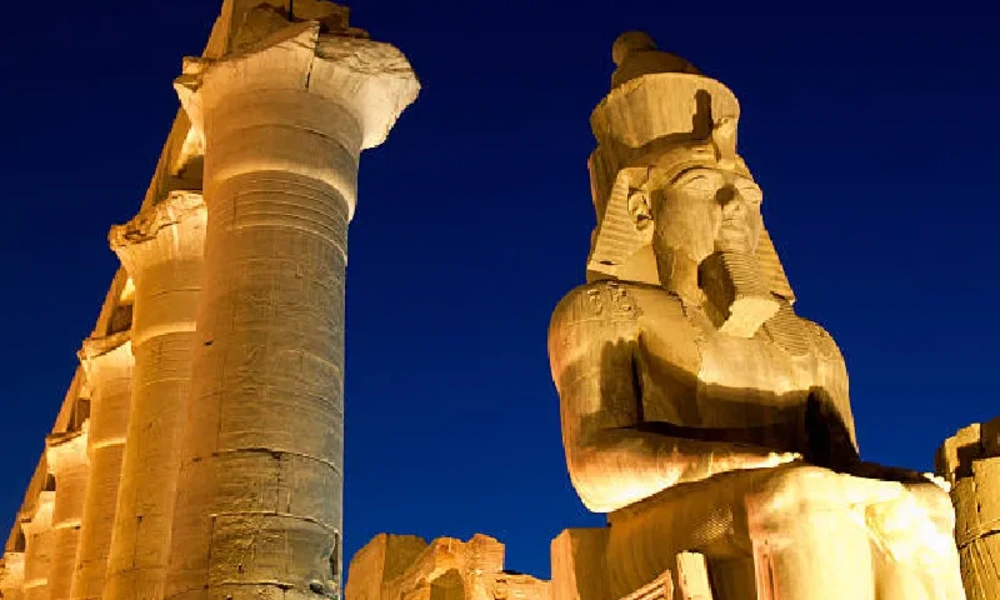 Beleuchteter Luxor-Tempel mit Statue von Ramses II. bei Nacht