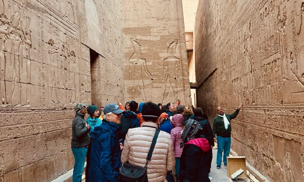 Reisegruppe mit Reiseleiter zwischen den Reliefwänden des Horus-Tempels in Edfu