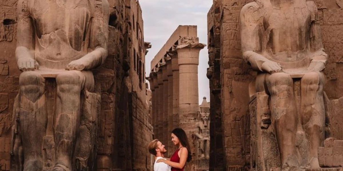 Couple posing romantically in front of Luxor Temple’s colossal seated statues and ancient stone architecture.