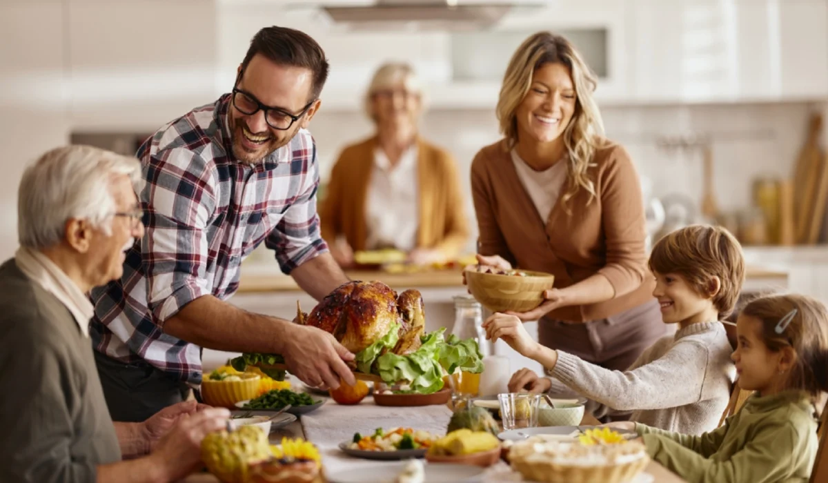 Family smiling around table with roasted turkey feast.