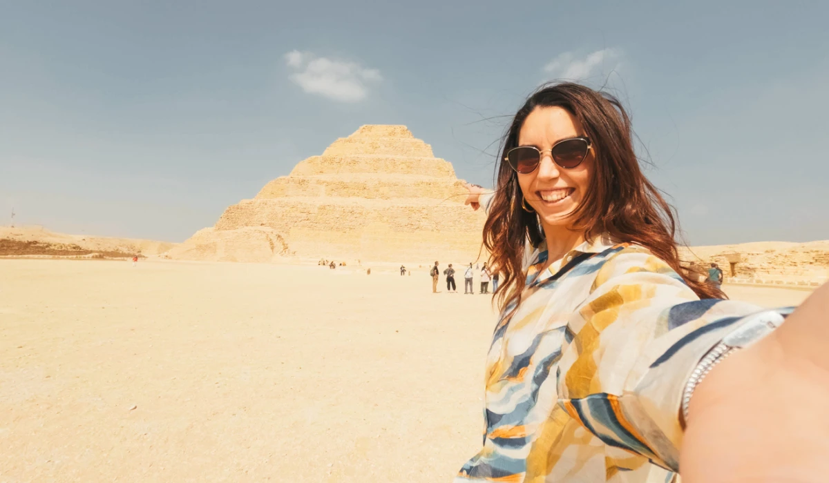 Tourist taking selfie with the step pyramid of djoser in saqqara, egypt