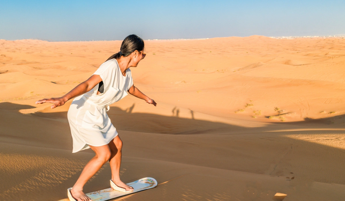 Young women sand surfing at the sand dunes of Dubai United Arab Emirates