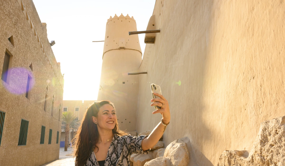 Woman taking selfie with phone at historic Al Masmak