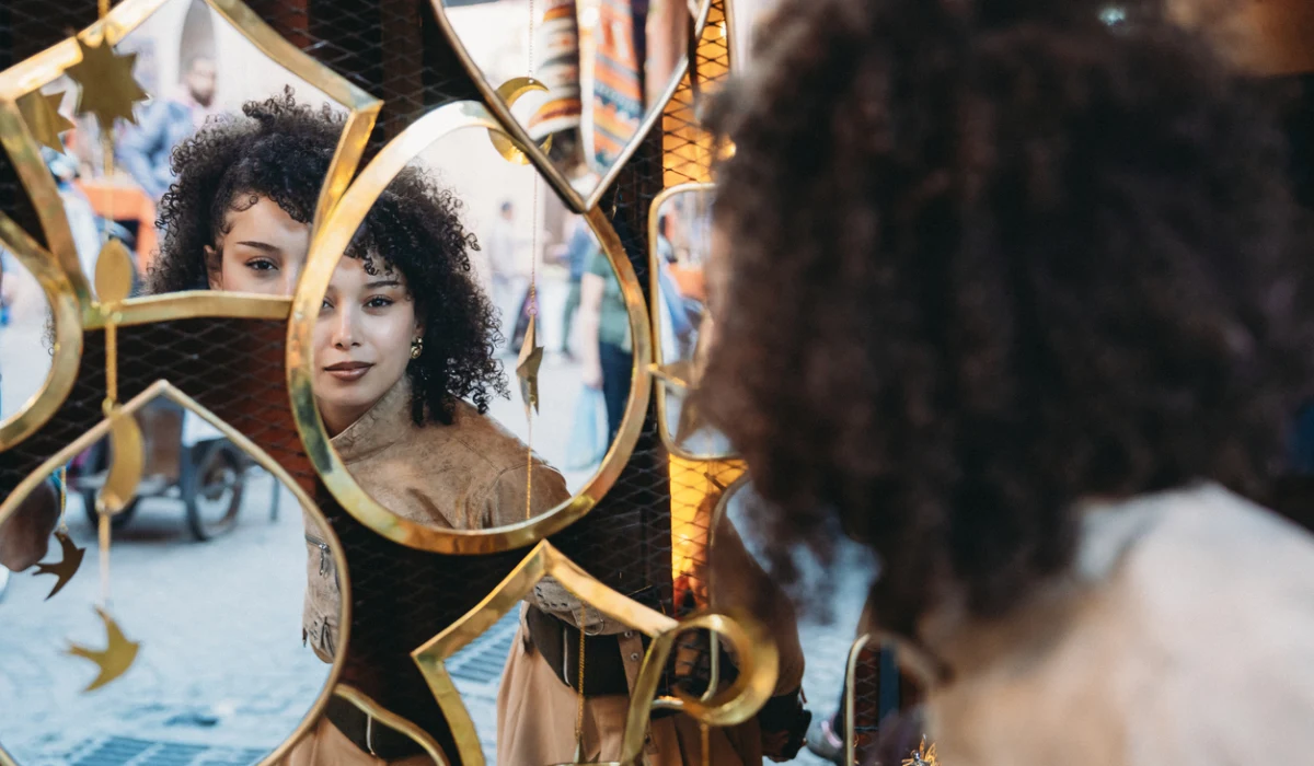 Woman seeing reflection in decorative Marrakech souk mirror
