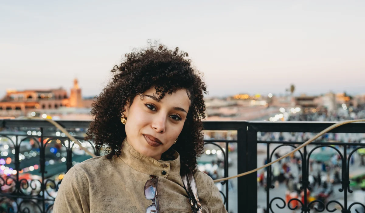 Young woman exploring Marrakech at dusk, rooftop view of Koutoubia and Jemaa el-Fna square