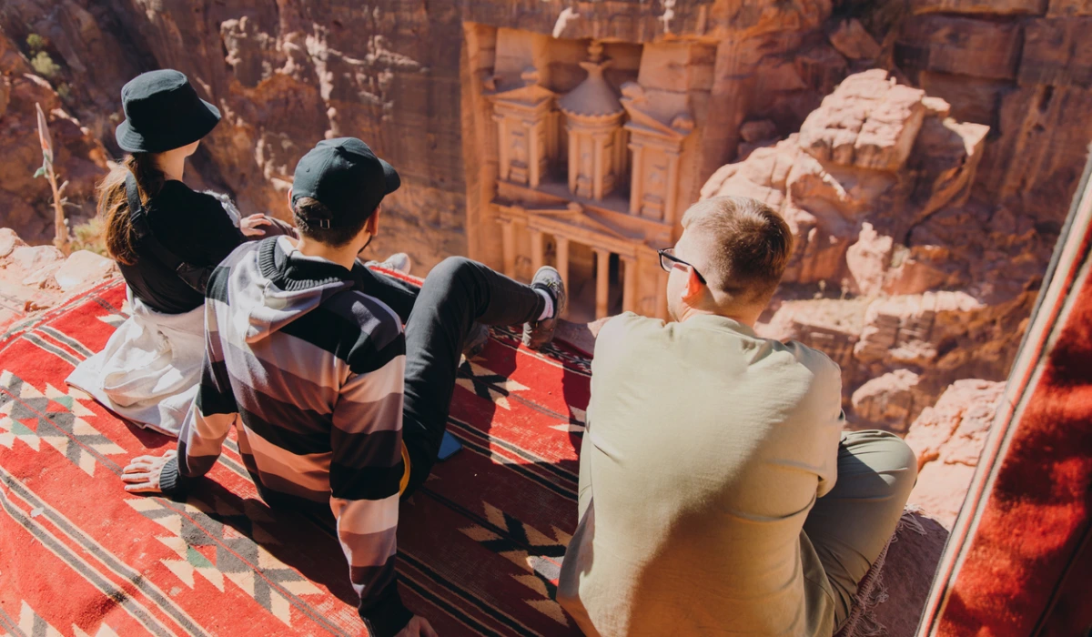 Friends travelers contemplating the scenic view of ancient Petra from mountain top