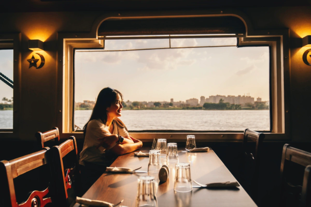 Restaurant eines Nilkreuzfahrtschiffs mit Blick auf den Nil bei Sonnenuntergang