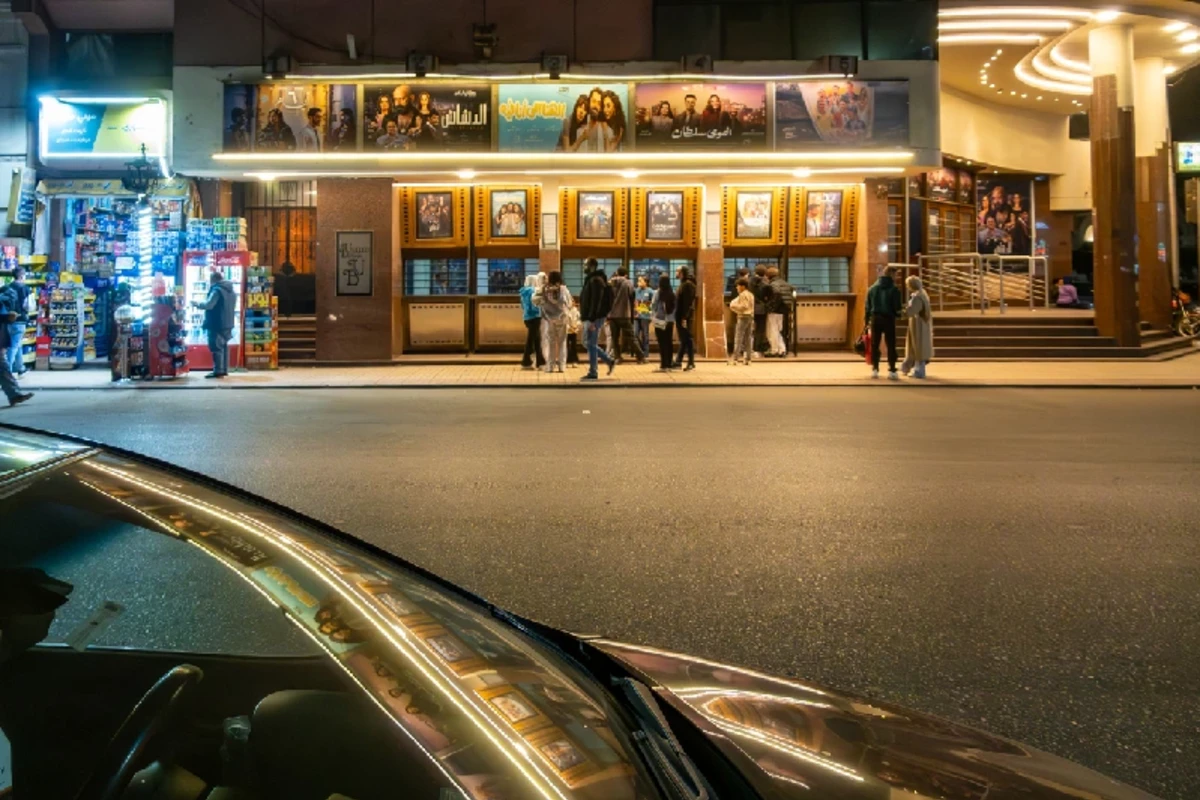 Menschen nachts in der Innenstadt in einer Schlange vor einem Kino.