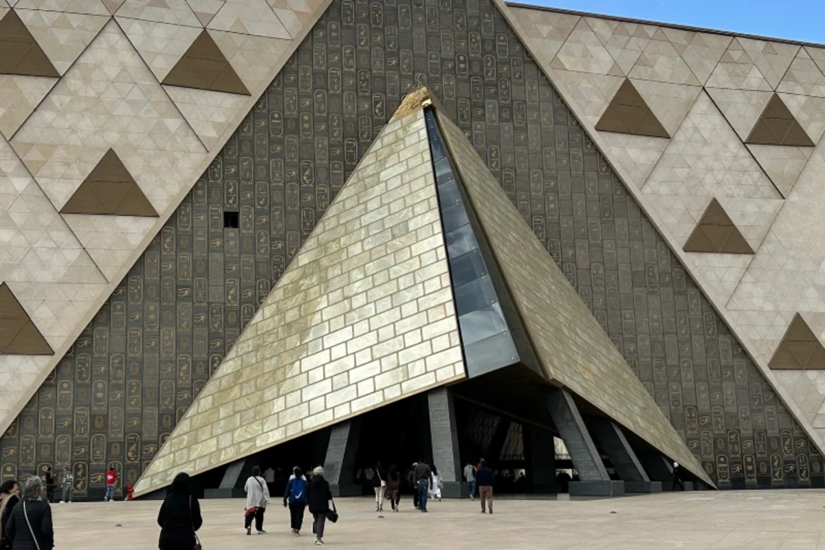 Eingang des Grand Egyptian Museum in Gizeh mit dreieckiger Alabasterfassade und Besuchern