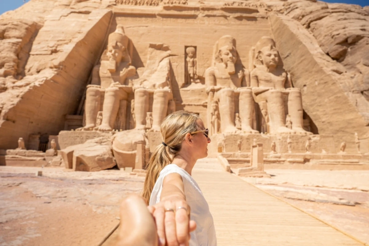 Frau vor den Kolossalstatuen des Felsentempels von Abu Simbel hält die Hand ihres Partners