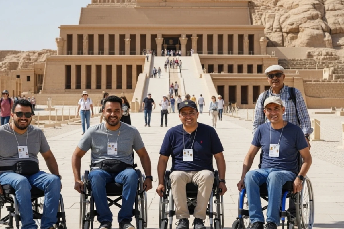   Six smiling tourists, including four wheelchair users and two standing companions, pose in front of the grand Mortuary Temple of Hatshepsut in Luxor—celebrating accessible travel at a historic Egyptian site.
