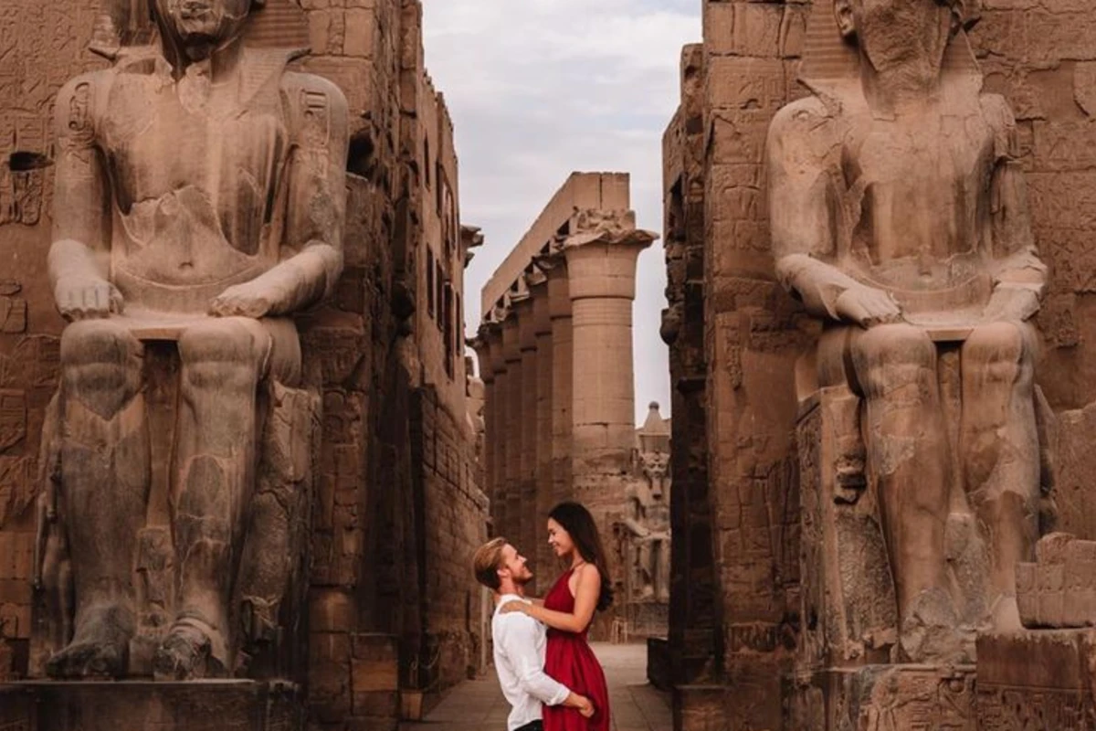 Couple posing romantically in front of Luxor Temple’s colossal seated statues and ancient stone architecture.