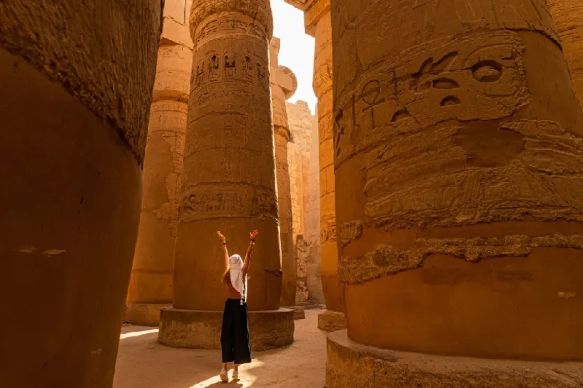 Turista caminando entre las columnas de la Gran Sala Hipóstila del Templo de Karnak , Viaje a Egipto Todo Incluido