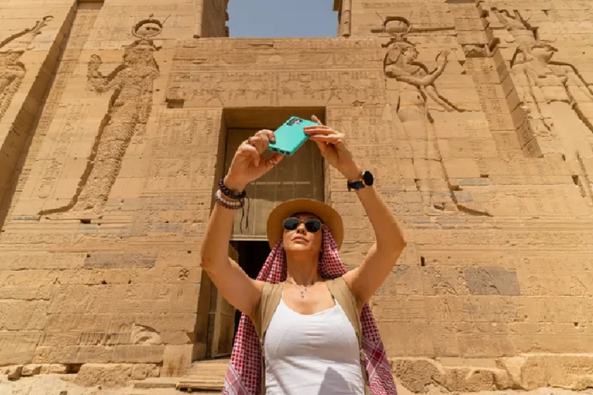 Mujer caminando por el Templo de Filae, también conocido como Templo de Isis, en Asuán, Egipto, mientras se toma un selfie, Viaje a Egipto Todo Incluido