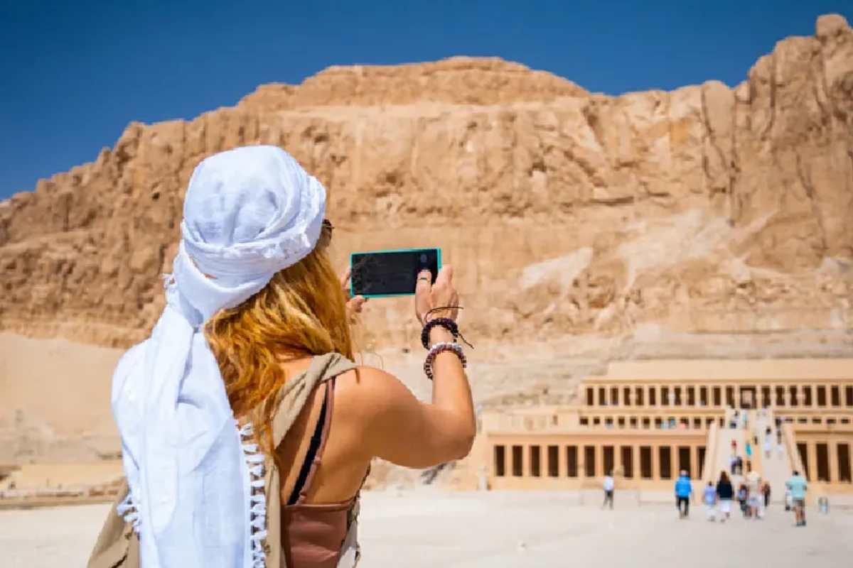 Mujer usando su smartphone para fotografiar el Templo de la Reina Hatshepsut, Viaje a Egipto Todo Incluido