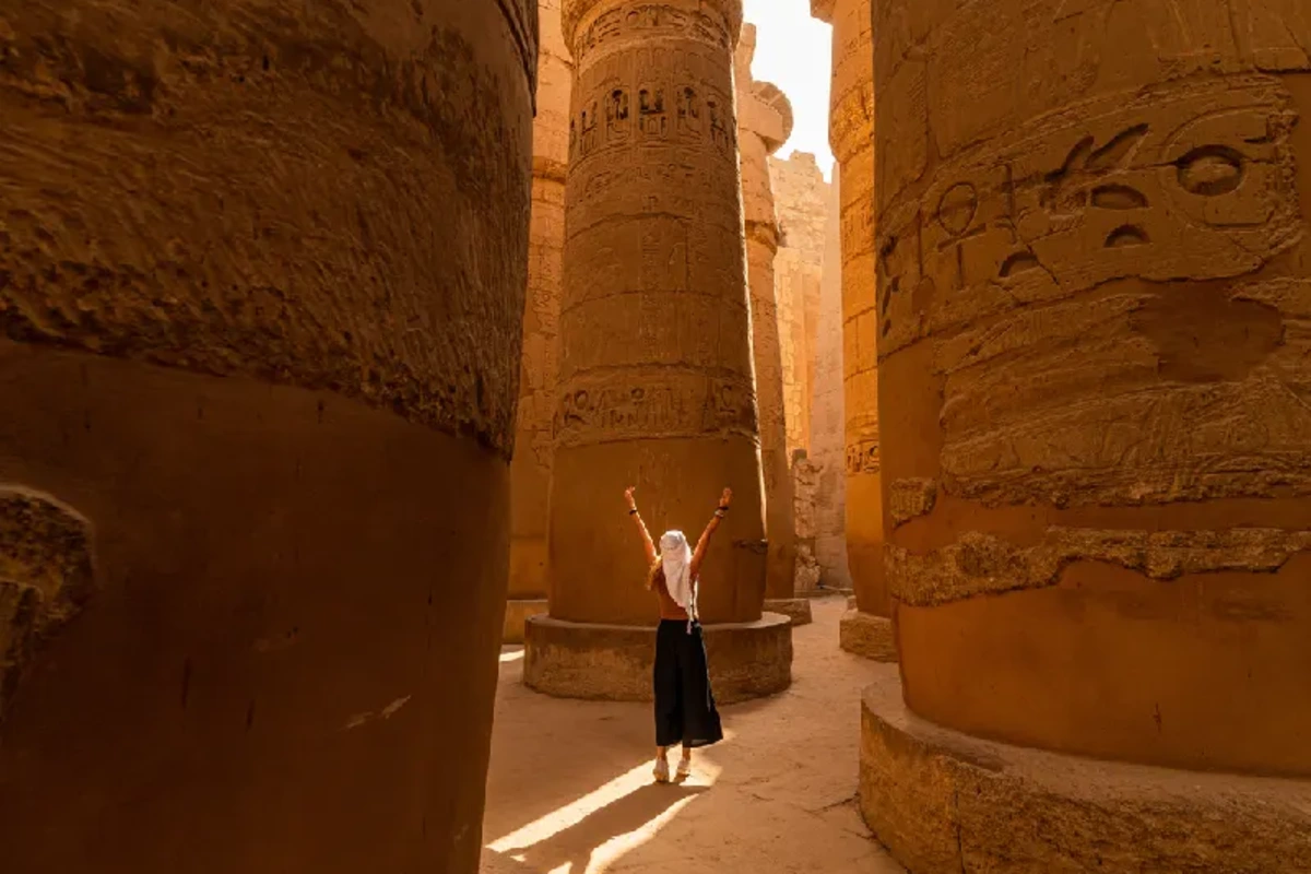 Turista caminando entre las columnas de la Gran Sala Hipóstila del Templo de Karnak, Crucero por el Nilo de lujo