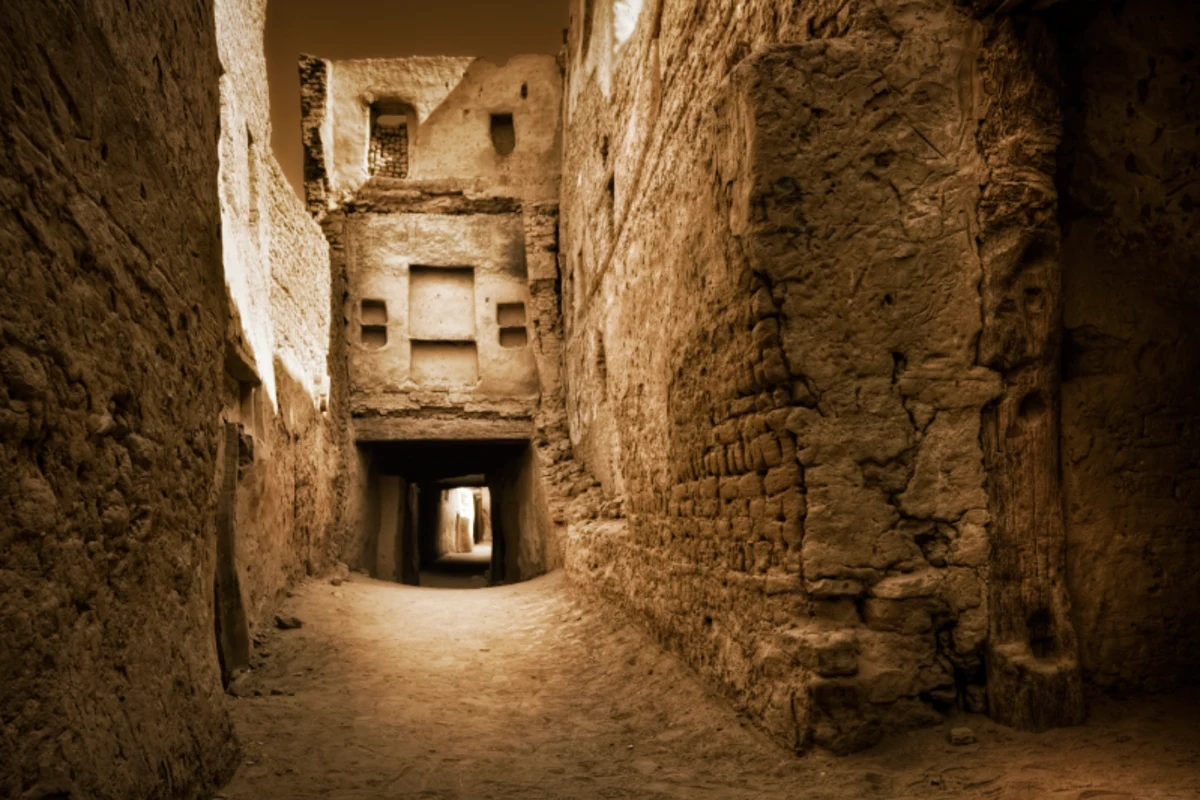 Enger, verlassener Gasse mit altem Torbogen und warmem Licht.