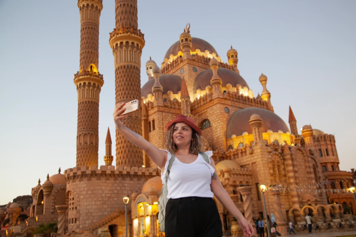 Frau mit rotem Hut macht ein Selfie vor der Al-Sahaba-Moschee in Sharm El Sheikh.