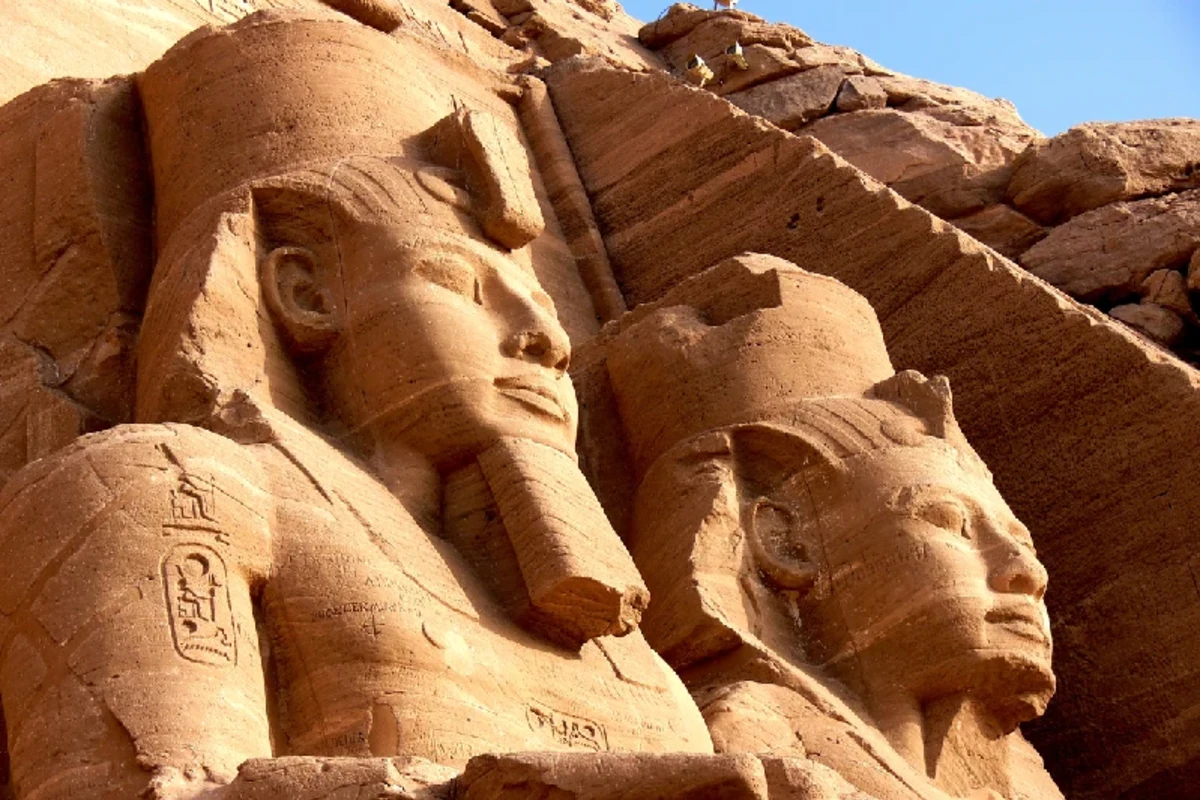 Ägyptische Pyramiden und antike Statuen im warmen Licht der untergehenden Sonne.