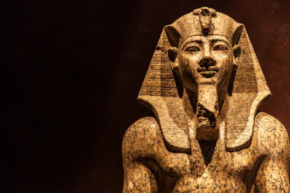 Historische Statue eines ägyptischen Pharaos mit kunstvollen Details und charakteristischen Merkmalen der altägyptischen Kunst.