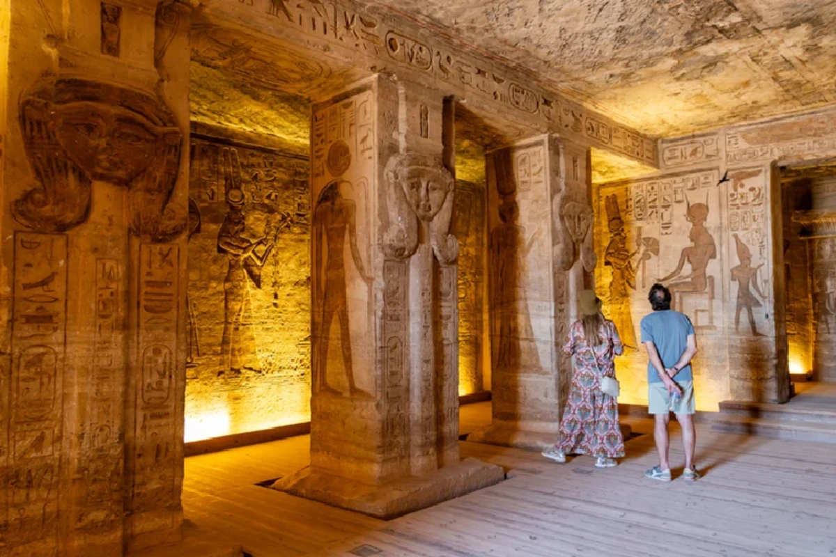 Besucher betrachten altägyptische Hieroglyphen im Inneren des Hathor-Tempels in Abu Simbel, Ägypten.