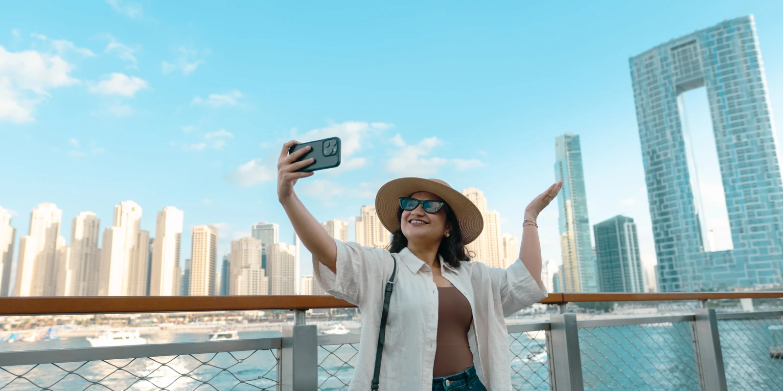 Young woman on the terrace of the hotel looking at Dubai Marina skyline with Address Beach resort and JBR buildings in background