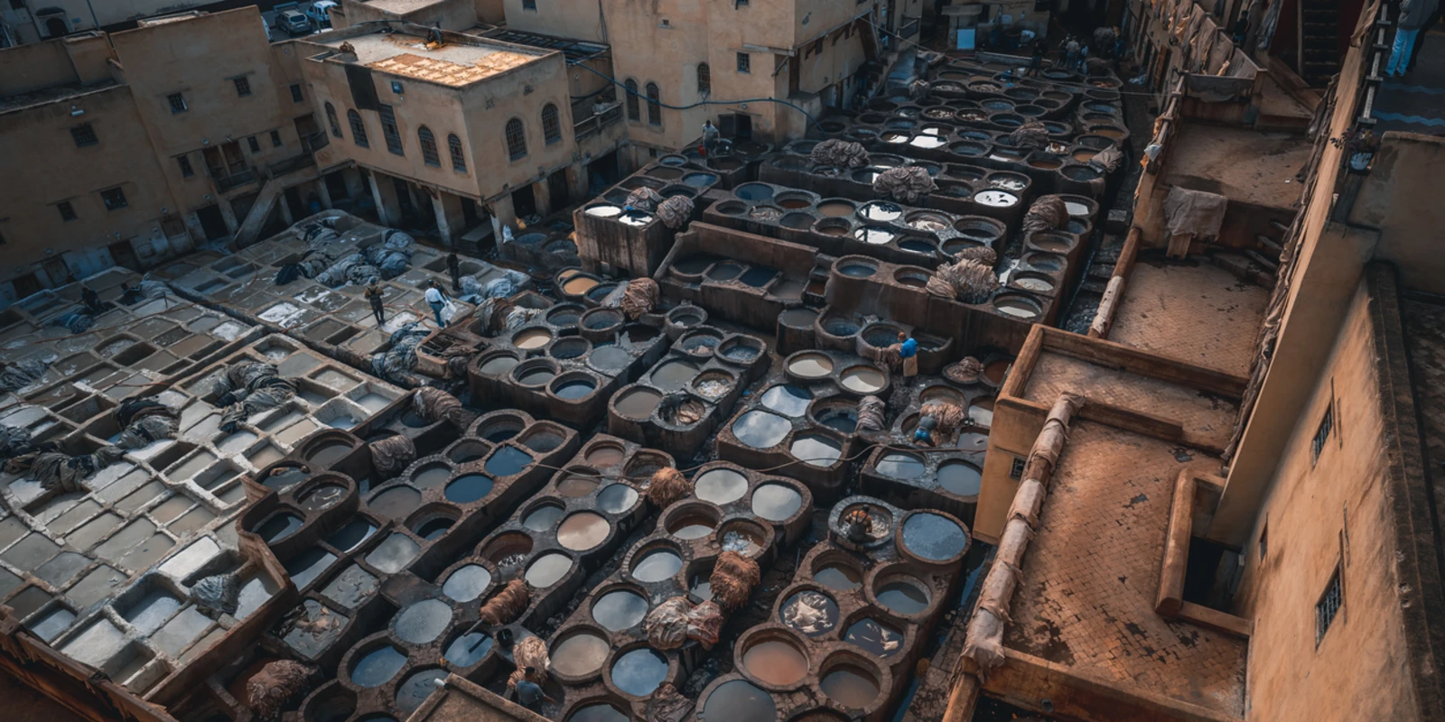 Men working at Chouwara Leather traditional tannery in ancient medina of Fes El Bali, Morocco, Africa.