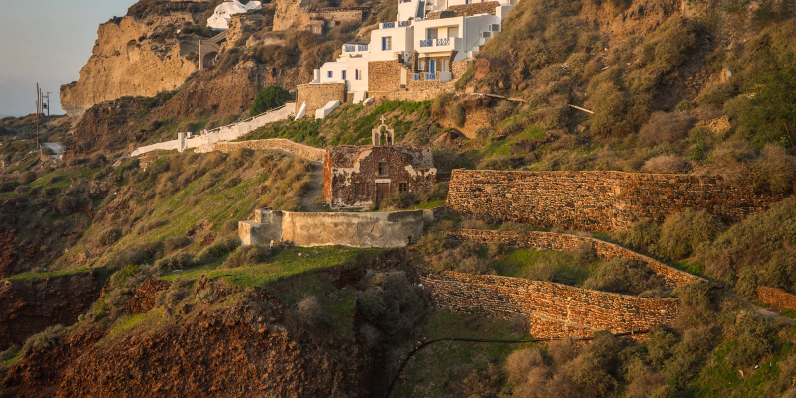 White city on a slope of a hill at sunset, Oia, Santorini, Greece