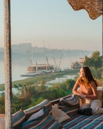 Joven sentada en la terraza mirando el Nilo al atardecer en Luxor
