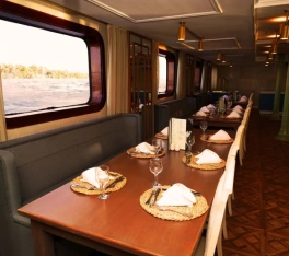 Restaurante panorámico del crucero por el Nilo Le Fayan II con mesas preparadas y vistas al río