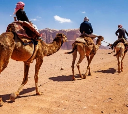 Viaggio organizzato Giordania, tre personi a dorso dei cammelli