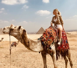 Viaggio al Cairo, una donna alle piramidi a dorso di un cammello