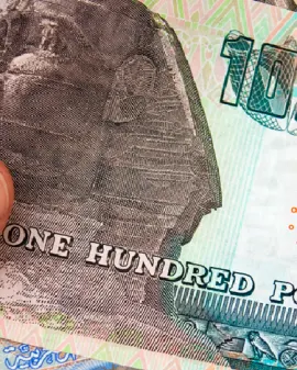 Un hombre sostiene moneda egipcia y un pasaporte que contiene una visa egipcia.