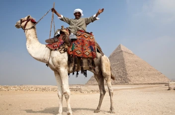 Hombre montando un camello frente a las Pirámides de Guiza.
