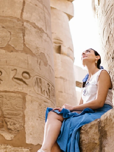 Vista trasera de un turista disfrutando de un recorrido por los pilares del Templo de Karnak en Egipto.