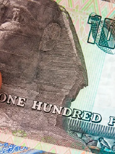 Un hombre sostiene moneda egipcia y un pasaporte que contiene una visa egipcia.
