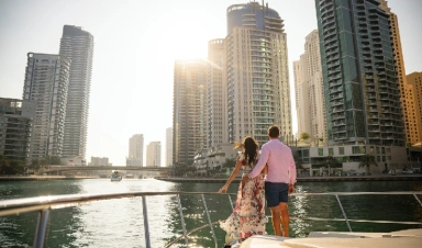 Un hombre y una mujer de vacaciones en los Emiratos Árabes Unidos, mirando hacia Dubai Marina al atardecer.
