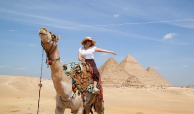 Turista paseando en camello en las pirámides de guiza durante su viaje a Egipto con abu simbel 