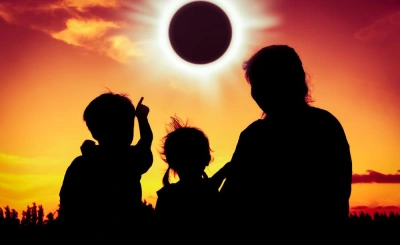 Family wearing certified solar viewers watching a total solar eclipse in a glowing sky