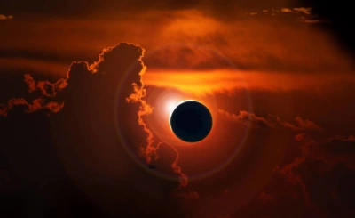 Total solar eclipse with the sun's corona breaking through red cloud