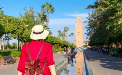 Woman in red gazes at Marrakech’s Koutoubia Mosque.