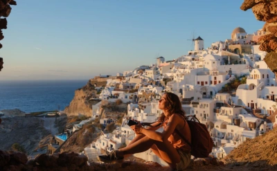 Woman in Oia, Santorini, photographing in awe.