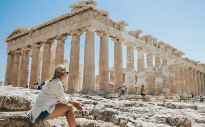 A woman unwinding as she gazes at the majestic Parthenon in Athens.