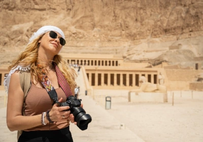 Fotógrafa de vacaciones con cámara frente al increíble Templo de la Reina Hatshepsut, Luxor, Egipto