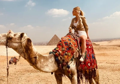 una ragazza seduta sul cammello davanti alle piramidi, tour oasi egitto  