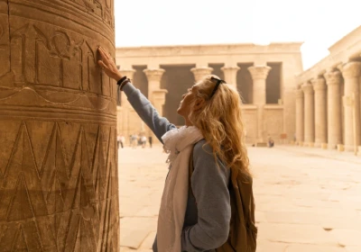 turista tocca le colonne del tempio di horus a edfu, tour egitto capodanno