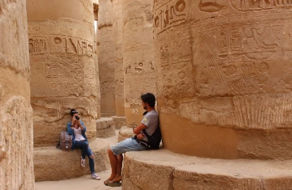 Pareja joven tomándose fotografías entre las columnas de la sala hipóstila del templo de Karnak en Luxor, Egipto.