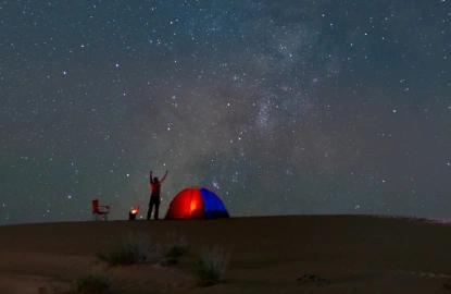 Persona acampando bajo la Vía Láctea en el desierto.