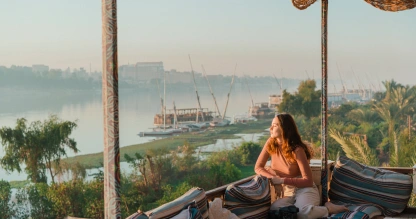 Joven sentada en la terraza mirando el Nilo al atardecer en Luxor