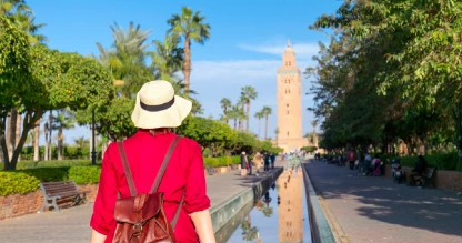 Woman in red gazes at Marrakech’s Koutoubia Mosque.